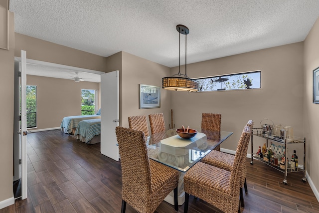 dining area featuring dark wood-type flooring, a textured ceiling, and baseboards