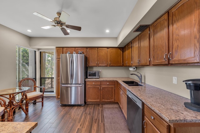 kitchen featuring stainless steel appliances, dark wood finished floors, brown cabinets, and a sink