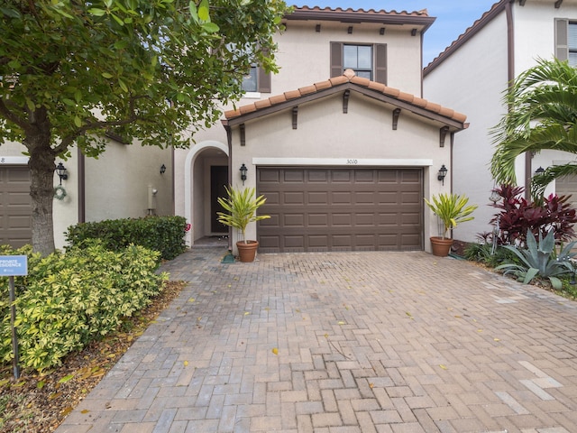 mediterranean / spanish house featuring stucco siding, decorative driveway, and a tiled roof