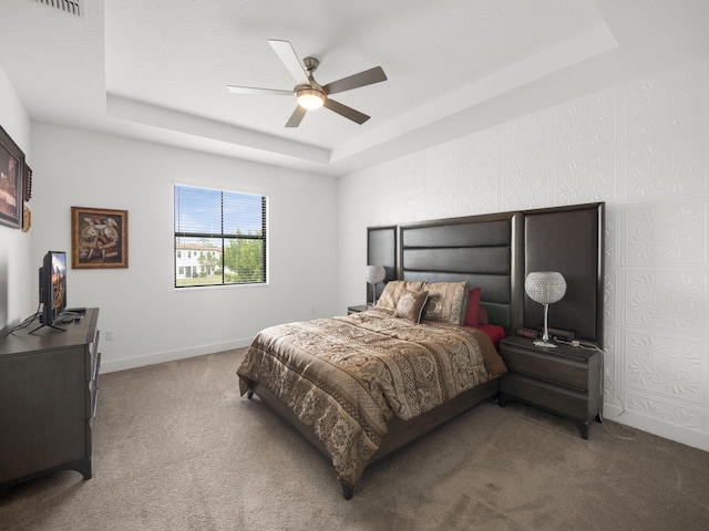 bedroom featuring carpet floors, a tray ceiling, a ceiling fan, and baseboards