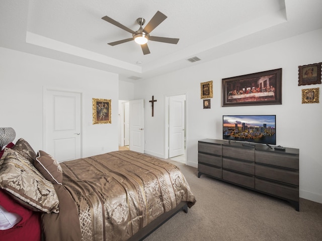 bedroom featuring a tray ceiling, carpet flooring, baseboards, and ceiling fan