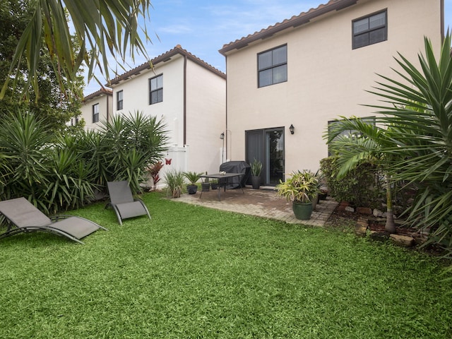 back of property featuring stucco siding, a yard, and a patio