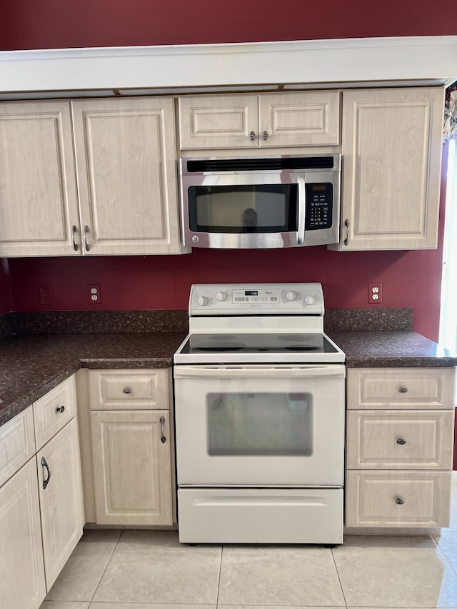 10694 Ocean Palm Way Unit 202, Boynton Beach, FL 33437 - kitchen with stainless steel microwave, electric range, light tile patterned floors, dark countertops, and light brown cabinets