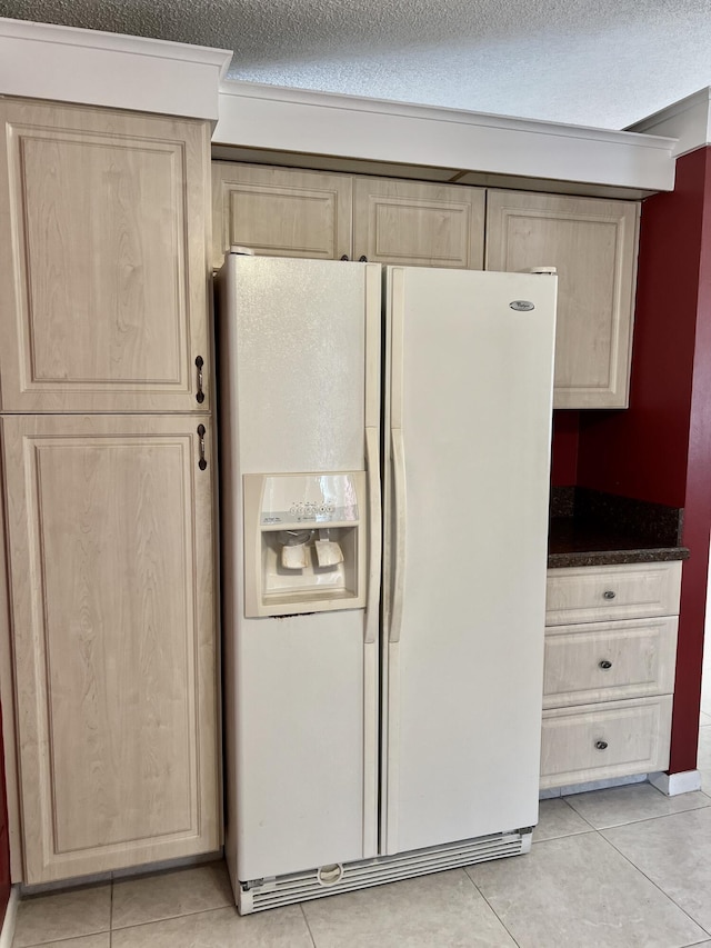 10694 Ocean Palm Way Unit 202, Boynton Beach, FL 33437 - kitchen featuring white fridge with ice dispenser, light brown cabinetry, light tile patterned flooring, a textured ceiling, and dark countertops