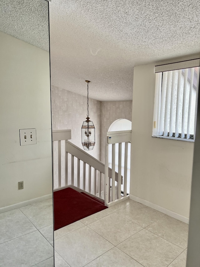 10694 Ocean Palm Way Unit 202, Boynton Beach, FL 33437 - stairway with tile patterned flooring, a textured ceiling, baseboards, and a chandelier