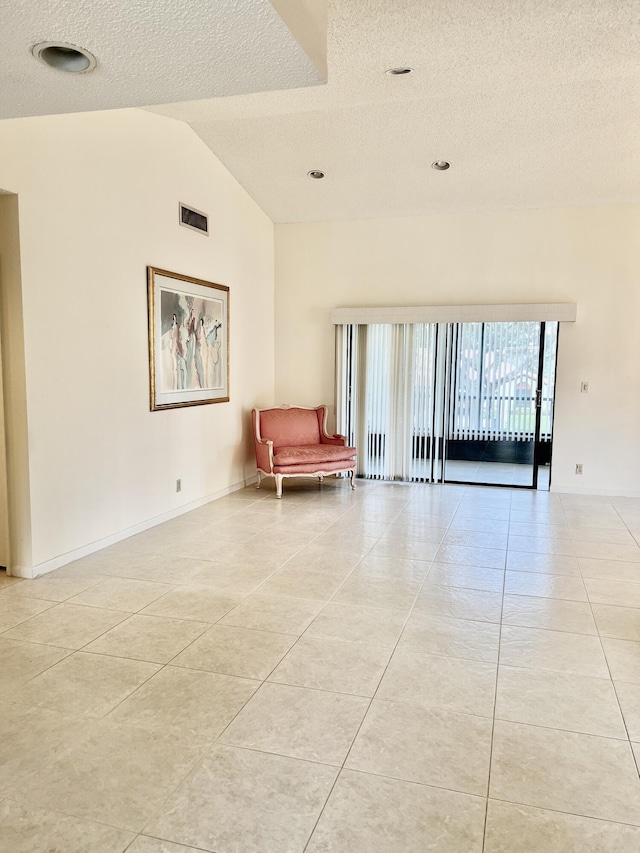 10694 Ocean Palm Way Unit 202, Boynton Beach, FL 33437 - living area with a textured ceiling, light tile patterned flooring, lofted ceiling, and baseboards