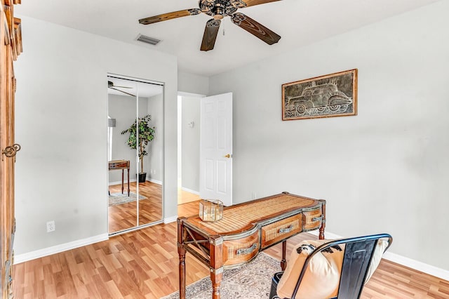 office area with light wood-style floors, baseboards, visible vents, and ceiling fan