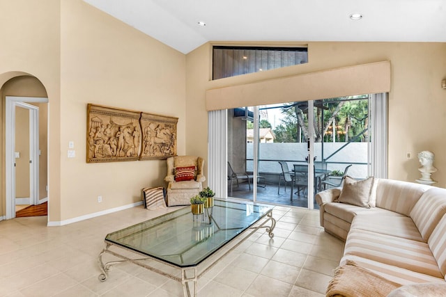 living room with arched walkways, recessed lighting, light tile patterned flooring, high vaulted ceiling, and baseboards