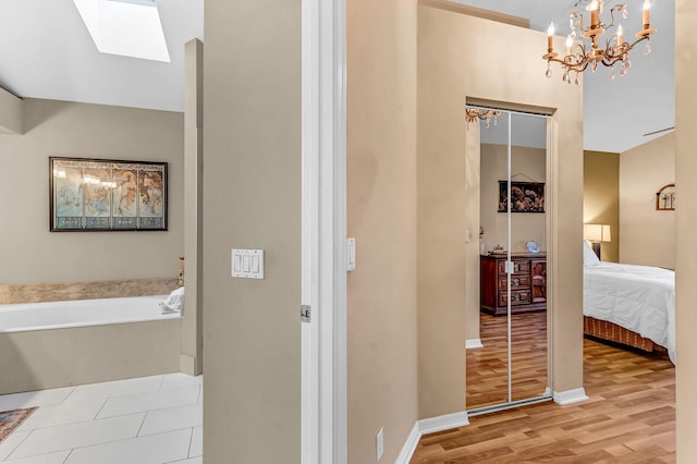 ensuite bathroom with wood finished floors, baseboards, ensuite bathroom, and a bath