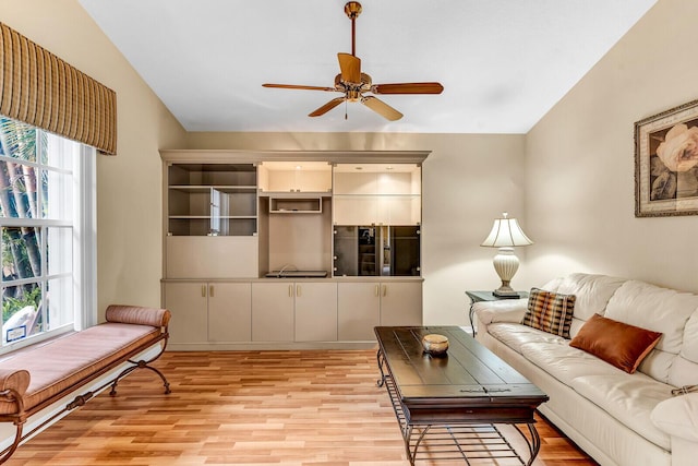 living room with vaulted ceiling, light wood finished floors, and a ceiling fan