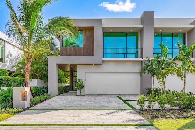 view of front facade featuring a garage, decorative driveway, and stucco siding