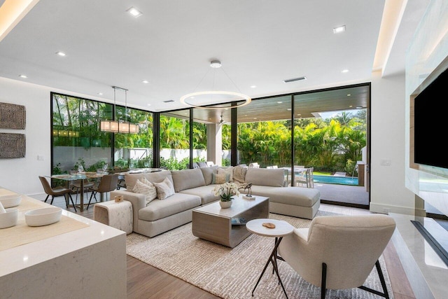 living room with a wall of windows, wood finished floors, and recessed lighting