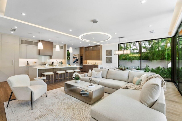 living area featuring light wood-style floors, recessed lighting, floor to ceiling windows, and visible vents