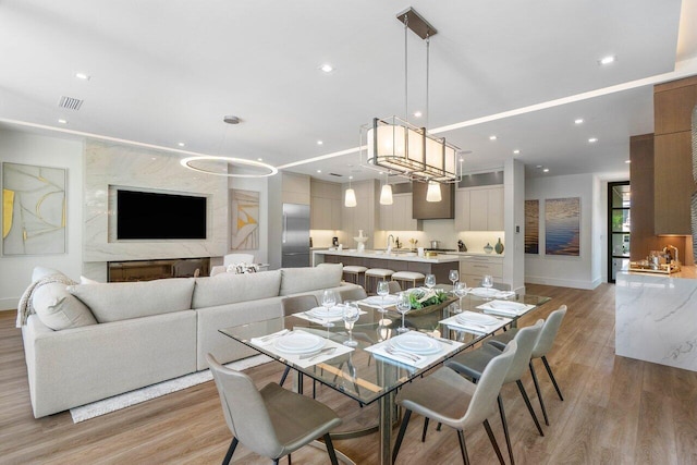 dining area with baseboards, light wood finished floors, visible vents, and recessed lighting