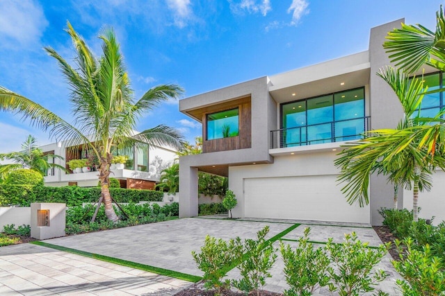 contemporary home with decorative driveway, an attached garage, and stucco siding