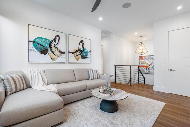 living area featuring ceiling fan with notable chandelier, recessed lighting, visible vents, and wood finished floors