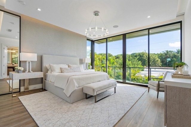 bedroom with a wall of windows, visible vents, a notable chandelier, and wood finished floors