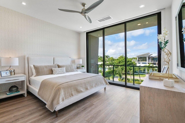 bedroom featuring visible vents, access to exterior, light wood-style floors, a wall of windows, and wallpapered walls