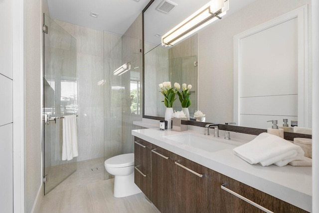 bathroom with toilet, a stall shower, vanity, and visible vents