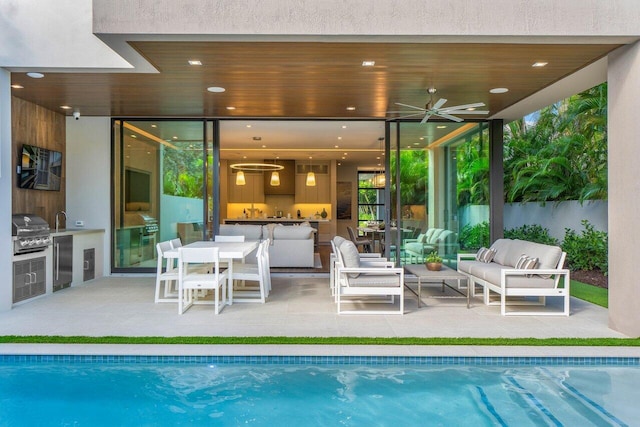 pool with exterior kitchen, a patio area, an outdoor living space, and area for grilling