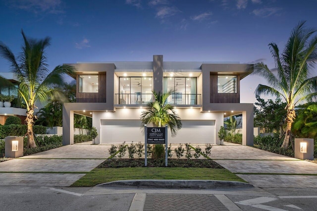 contemporary home featuring decorative driveway, an attached garage, and stucco siding