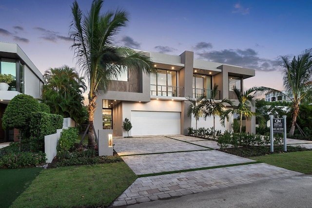 view of front of property with a garage, decorative driveway, a balcony, and stucco siding