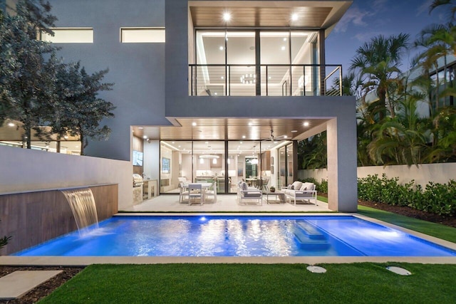 back of property featuring fence, stucco siding, outdoor lounge area, a fenced in pool, and a balcony