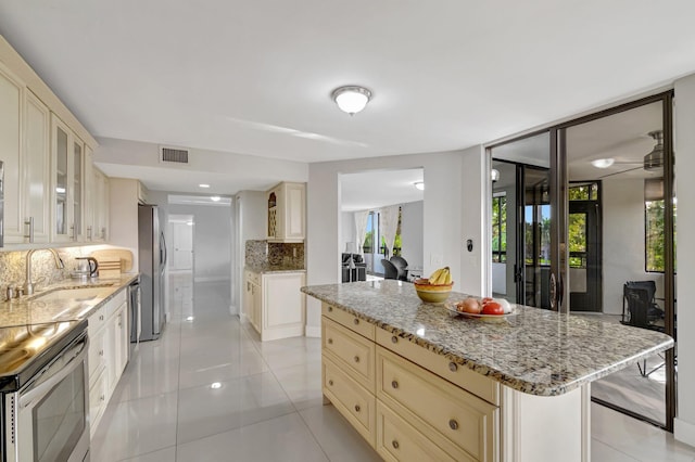 kitchen featuring stainless steel appliances, visible vents, glass insert cabinets, a kitchen island, and a sink