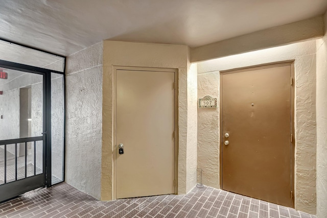 interior space with brick floor and a textured wall