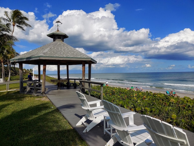 view of property's community featuring a gazebo, a lawn, a water view, and a beach view