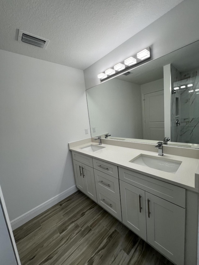 full bath with double vanity, a marble finish shower, a sink, and visible vents