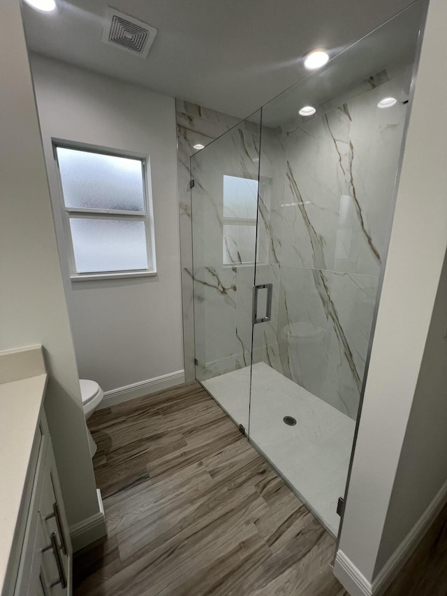 full bath featuring visible vents, toilet, vanity, wood finished floors, and baseboards