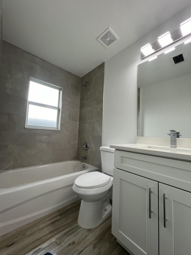 full bath featuring shower / bathtub combination, visible vents, wood finished floors, and vanity