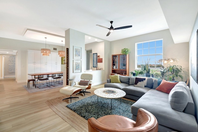 living room with ceiling fan, light wood finished floors, and baseboards