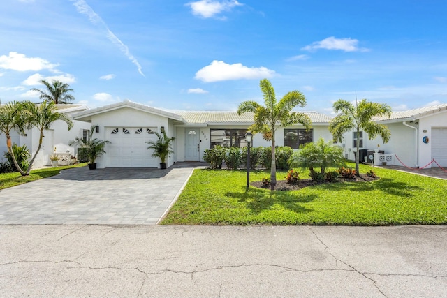 single story home featuring a garage, a tiled roof, decorative driveway, a front yard, and stucco siding