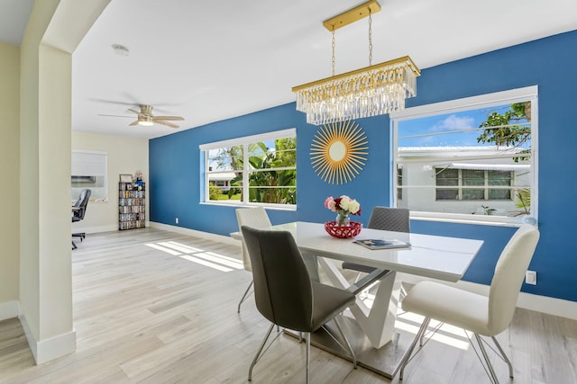 dining area with baseboards, light wood finished floors, and ceiling fan with notable chandelier