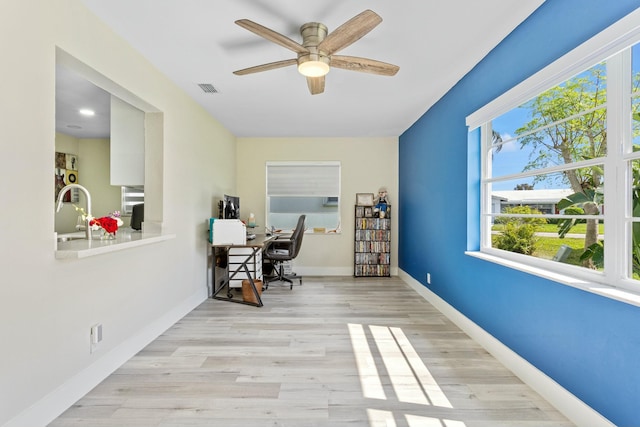 office space featuring a sink, a ceiling fan, visible vents, baseboards, and light wood-type flooring