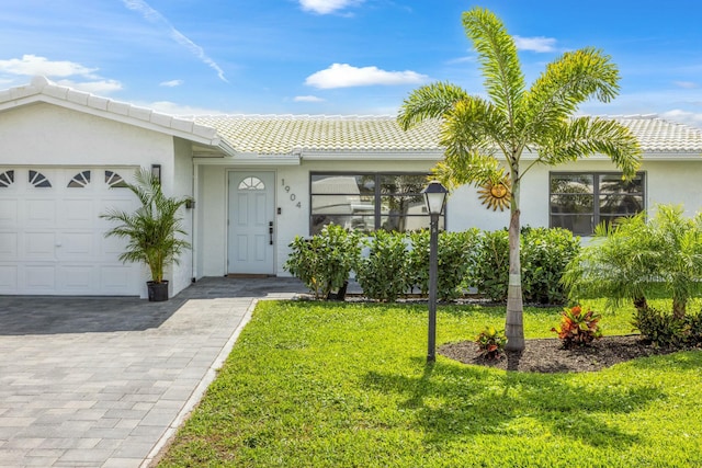 view of exterior entry with a garage, a yard, a tile roof, and stucco siding