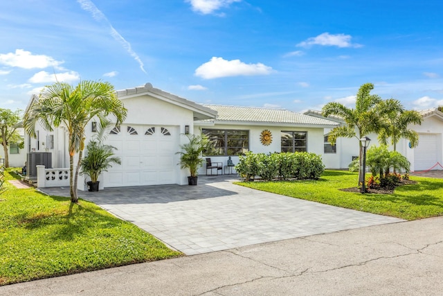 ranch-style house with a tile roof, an attached garage, decorative driveway, a front yard, and stucco siding