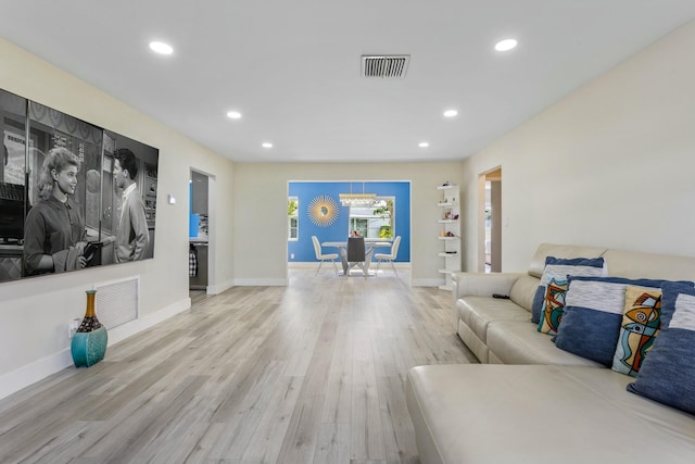 living room with light wood-style flooring, visible vents, baseboards, and recessed lighting