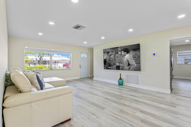 living area with light wood-style flooring, plenty of natural light, and visible vents