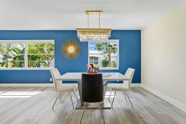 dining room with light wood-style floors, a notable chandelier, and baseboards