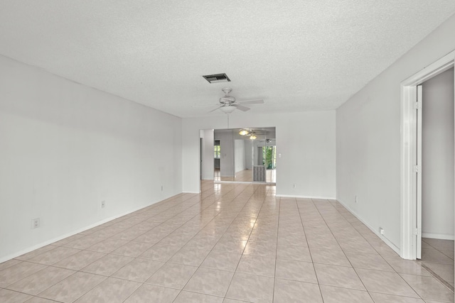 spare room featuring a textured ceiling, light tile patterned floors, visible vents, and ceiling fan