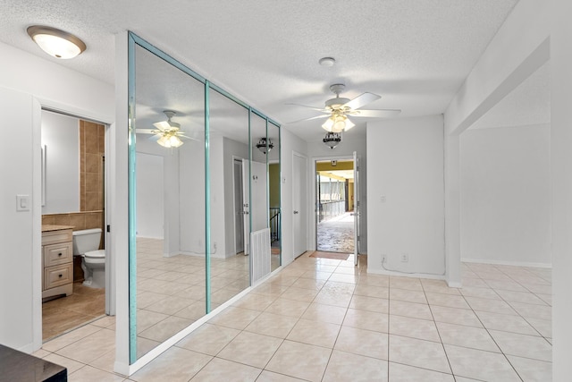 empty room with light tile patterned floors, a ceiling fan, and a textured ceiling