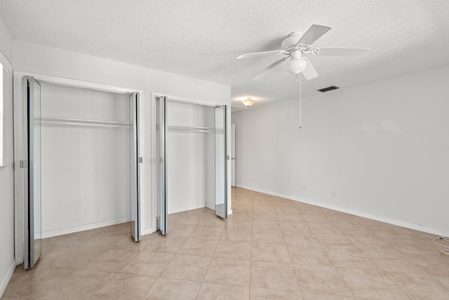 unfurnished bedroom with visible vents, multiple closets, a ceiling fan, a textured ceiling, and baseboards