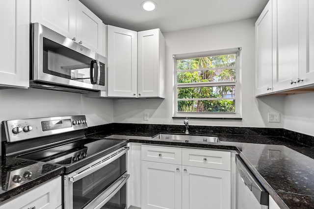 kitchen featuring dark stone countertops, recessed lighting, appliances with stainless steel finishes, white cabinetry, and a sink