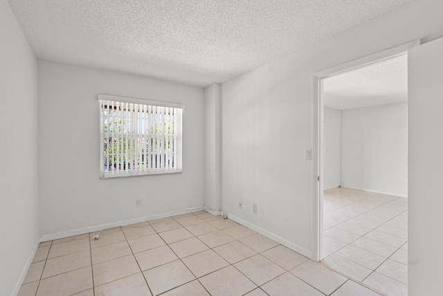 unfurnished room with light tile patterned floors, baseboards, and a textured ceiling