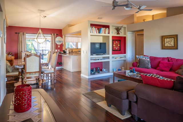 living room featuring lofted ceiling, ceiling fan, built in shelves, and dark wood-type flooring