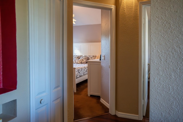 hall featuring baseboards and a textured wall