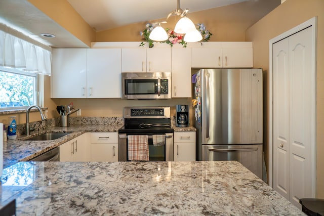 kitchen featuring light stone counters, pendant lighting, appliances with stainless steel finishes, white cabinetry, and a sink